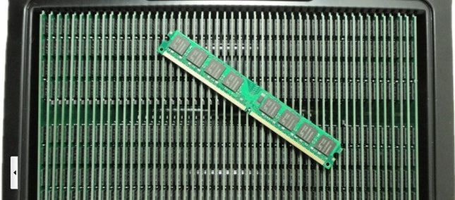 A single green desktop computer memory stick with chips lies diagonally on a tray of many.
