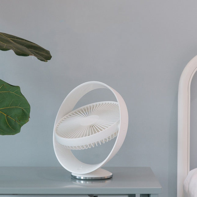 A white USB desk fan with a unique circular frame sits on a grey table.